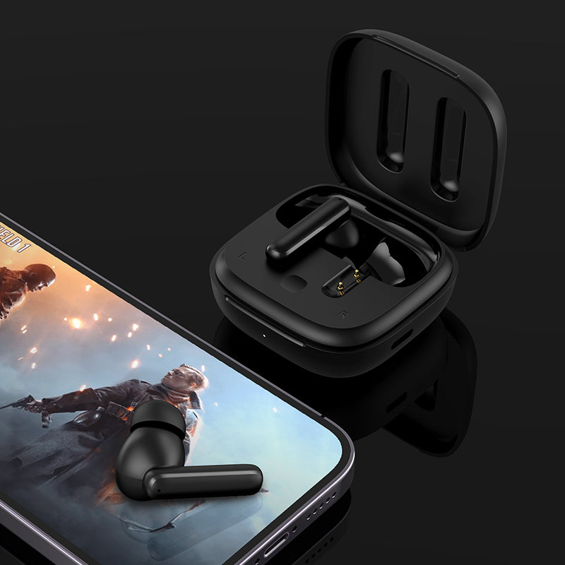 Black QCY T13 ANC with open case and single earbud beside phone showing gaming scene, diagonal composition on dark